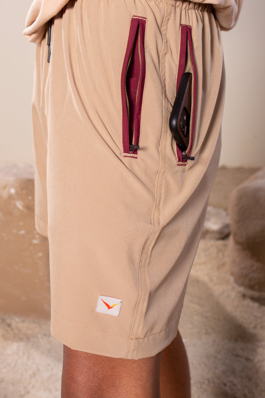 Men's Flight Shorts in Tan | VOLO Apparel | Designed so you can feel fly and completely secure, the Flight Shorts 2.0 are made with an ultralight micro stretch fabric that is quick drying and comes with a three zipper pocket design. The smart pocket tech makes it so your stuff won’t bounce when you do. Reinforced stitching so it can handle everything you will throw at it. The one short for your every adventure.