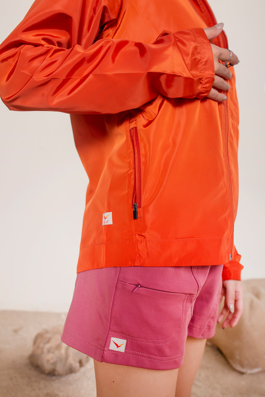 Women's Windansea Jacket in Orange | VOLO Apparel | The ultimate all year jacket, an ultralight hooded windbreaker, crafted with the revolutionary memory fabric and five pockets. This jacket is full of features, water repellant, three zipper pockets, UPF 50 protection from the sun and tailored fit to look super stylish while being ready for any adventure.
