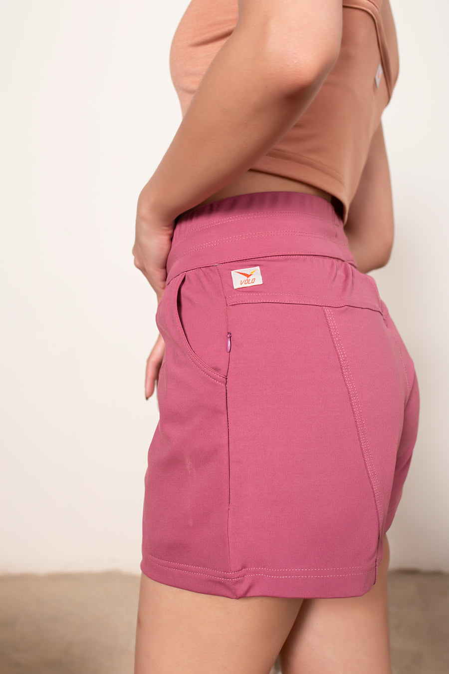 Women's Terra Shorts Garnet Pink | VOLO Apparel | A blend of technology, function, and style. The Terra shorts are designed and ready for every active opportunity that comes your way. Your first women's shorts with deep pockets, a snap button smart phone pocket, a zippered key pocket, and a hidden zippered back pocket.  High waisted, great for climbing, yoga, training, running and chilling.