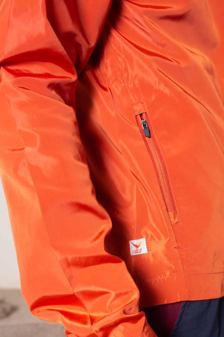 Men's Windansea Jacket in Orange | VOLO Apparel | The ultimate all year jacket, an ultralight hooded windbreaker, crafted with the revolutionary memory fabric and five pockets. This jacket is full of features, water repellant, three zipper pockets, UPF 50 protection from the sun and tailored fit to look super stylish while being ready for any adventure.
